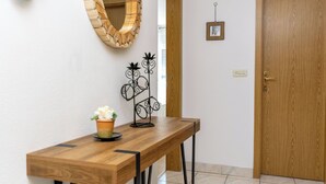 A wooden console table with a potted plant and a decorative metal piece.