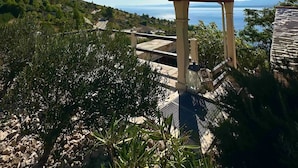 Una terraza con vistas al mar, rodeada de vegetación y un cielo despejado.