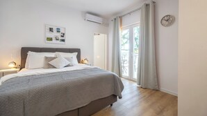 Ein Schlafzimmer mit einem Bett, Nachttischen, einer Wanduhr und einem Fenster mit Vorhängen.