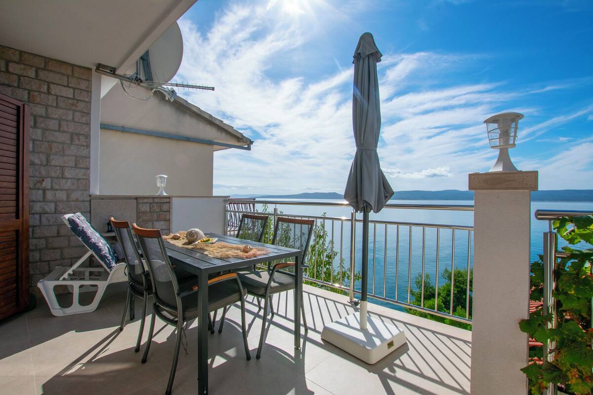 A balcony with a table and chairs, overlooking a body of water.