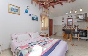 A bedroom with a bed, a desk, and a kitchenette. - Apartments Ivante (Omis)