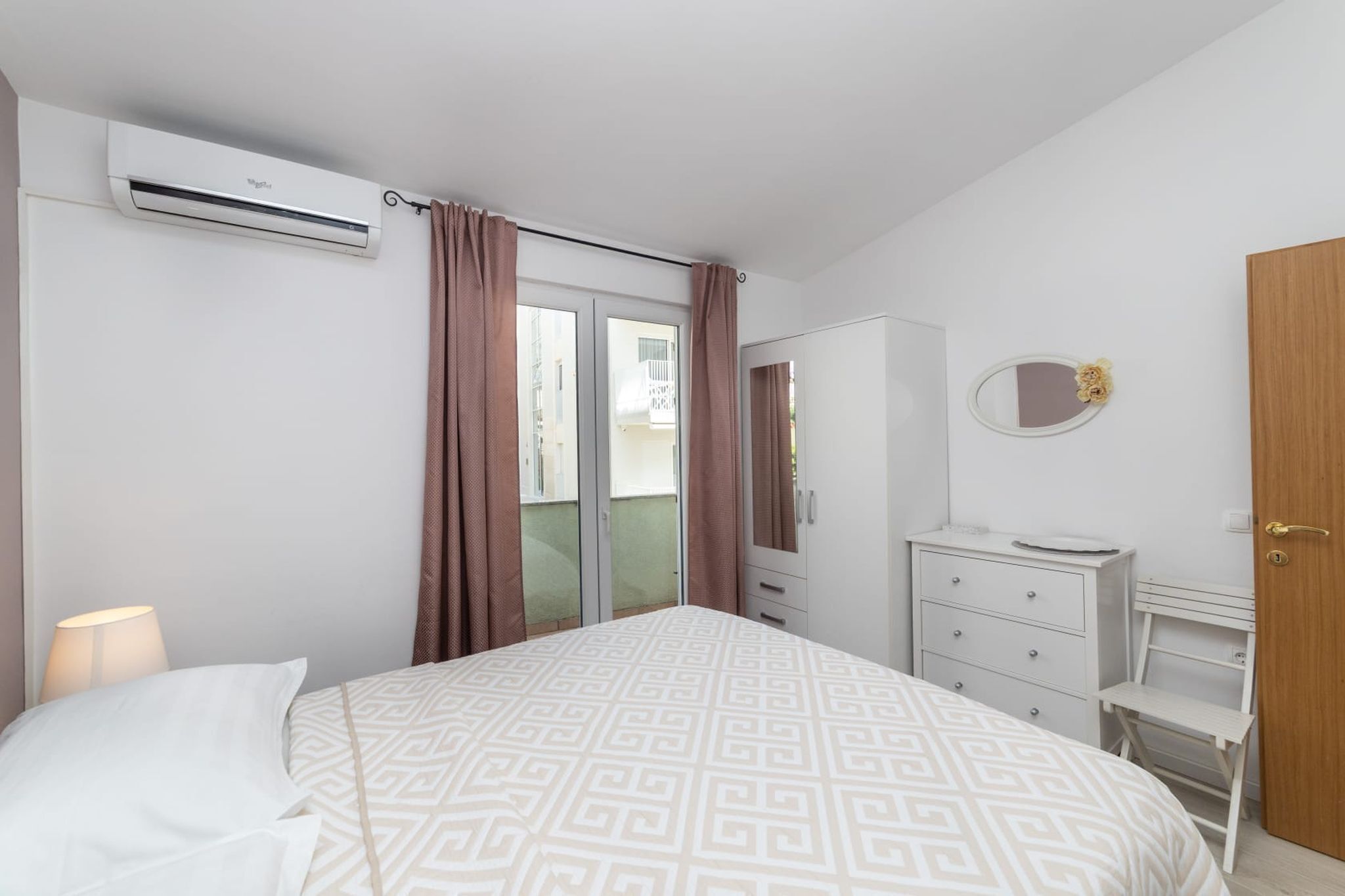 Une chambre à coucher comprenant un lit, une commode, un miroir et un appareil de climatisation.