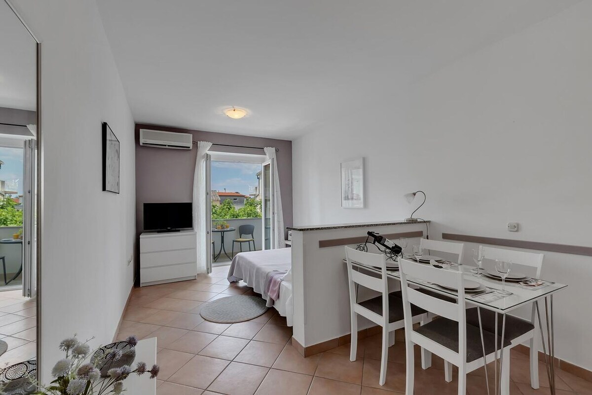 Ein kompaktes Hotelzimmer mit Balkon, Essbereich und Bett.