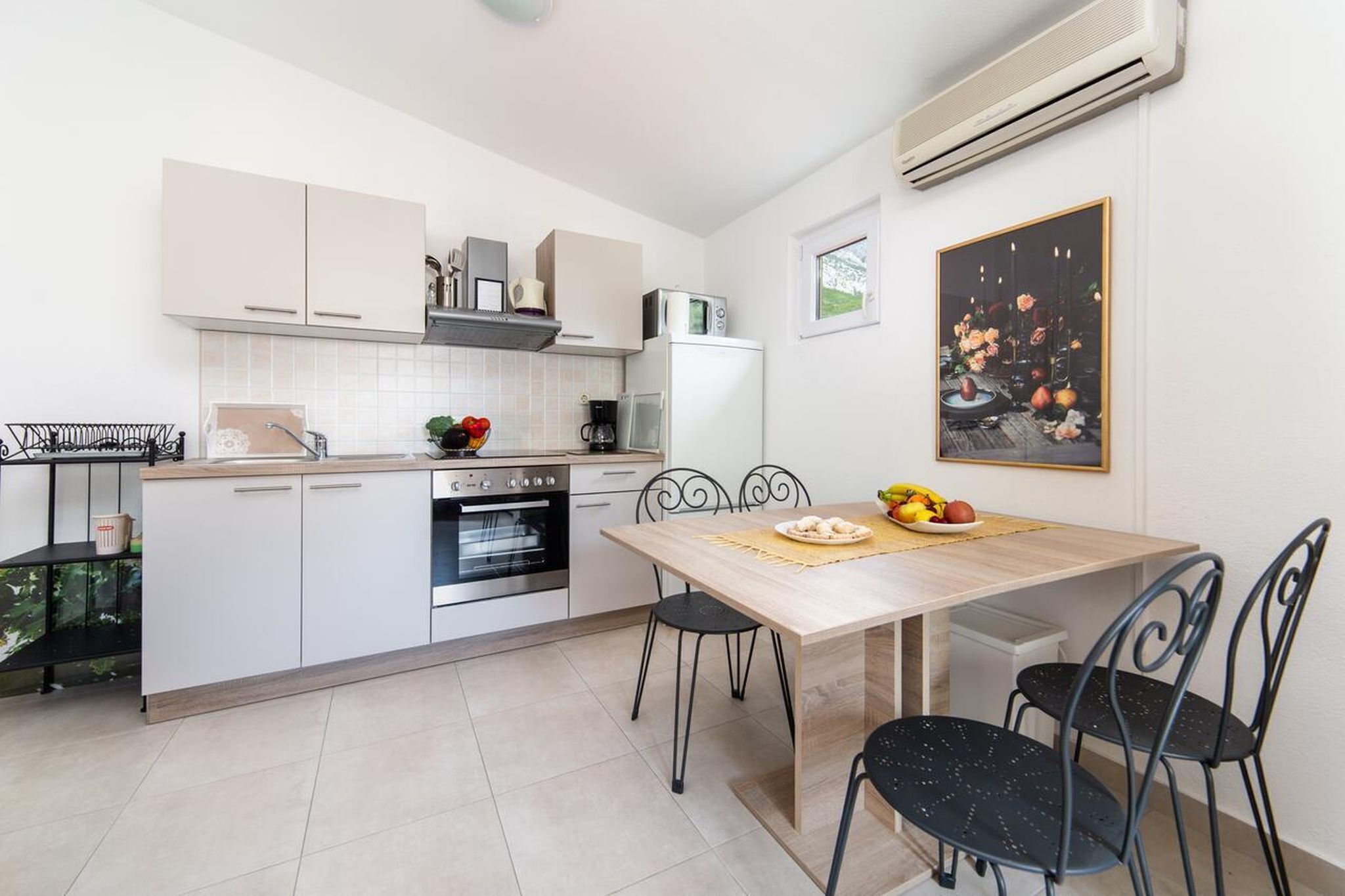 Una cucina moderna con mobili bianchi, un tavolo da pranzo in legno e sedie nere.