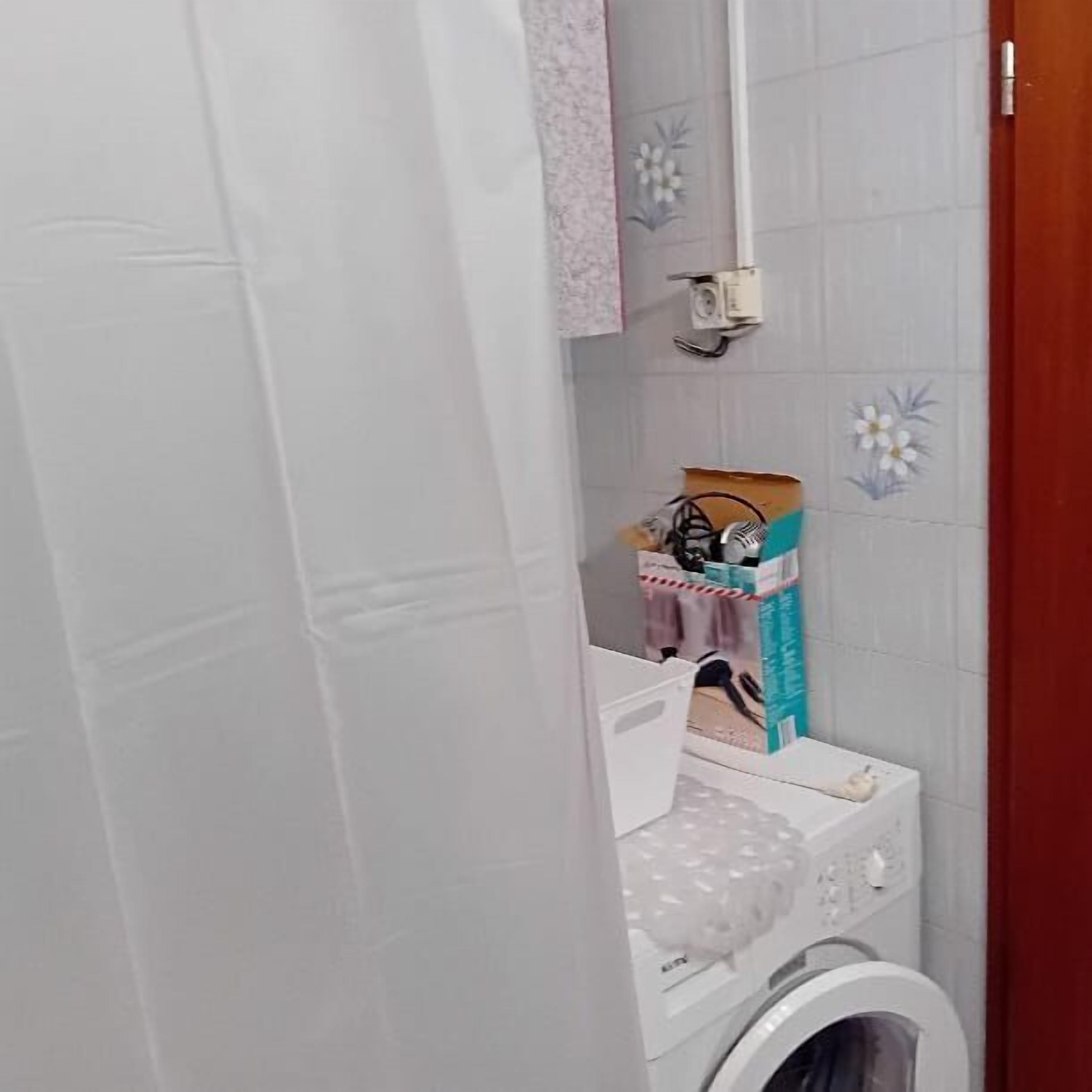 Une buanderie équipée d’un lave-linge, d’un sèche-linge et d’une petite étagère sur laquelle sont posés divers objets.
