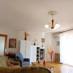 A living room with a sofa, armchair, coffee table, and a white cabinet. - Apartment Sunset Lina (Pula)