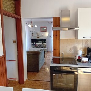 A modern kitchen with a built-in oven, a coffee machine, and a microwave. There is a dining area with a sofa and a television. - Apartment Sunset Lina (Pula)