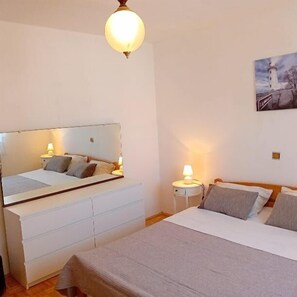 A bedroom with a bed, bedside tables, a mirror, and a painting on the wall. - Apartment Sunset Lina (Pula)