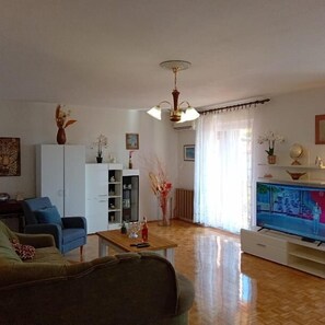 Ein Wohnzimmer mit einer Couch, einem Couchtisch, einem Fernseher und einem Schrank.
