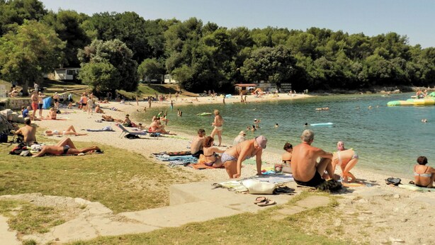 Ein Strand mit badenden und sonnenden Personen.