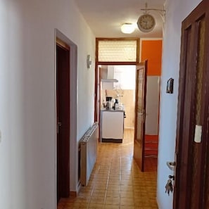 A narrow hallway with a radiator, a clock, and a door leading to a room. - Apartment Sunset Lina (Pula)