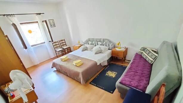 Camera d'albergo con un letto, una scrivania, una sedia, un tavolino e una finestra con tende.