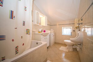 Een badkamer met een badkuip, toilet, wastafel en een raam.