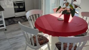 A dining area with a round table, white chairs, and a red tablecloth. - Apartment Jasmina (Nin)