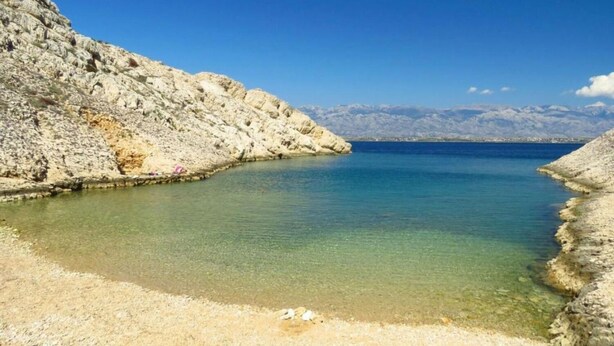 A coastal landscape with clear waters, rocky terrain, and distant mountains. - Apartment Jasmina (Nin)