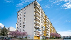 A multi-story residential building with balconies, a stone wall, and cherry blossom trees. - Apartment Slava (Rijeka)
