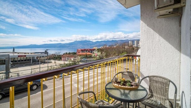 A balcony with a view of a body of water, mountains, and buildings. - Apartment Slava (Rijeka)