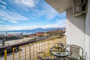 Varanda com vista para a água, montanhas e edifícios.