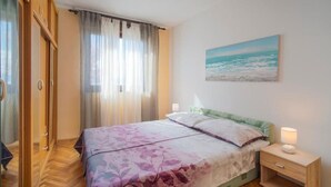 A bedroom with a bed, a nightstand, a lamp, a painting, and a wardrobe. - Apartment Slava (Rijeka)