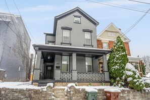 Une maison à deux étages avec une façade en briques, un porche à l’avant et une boîte aux lettres.