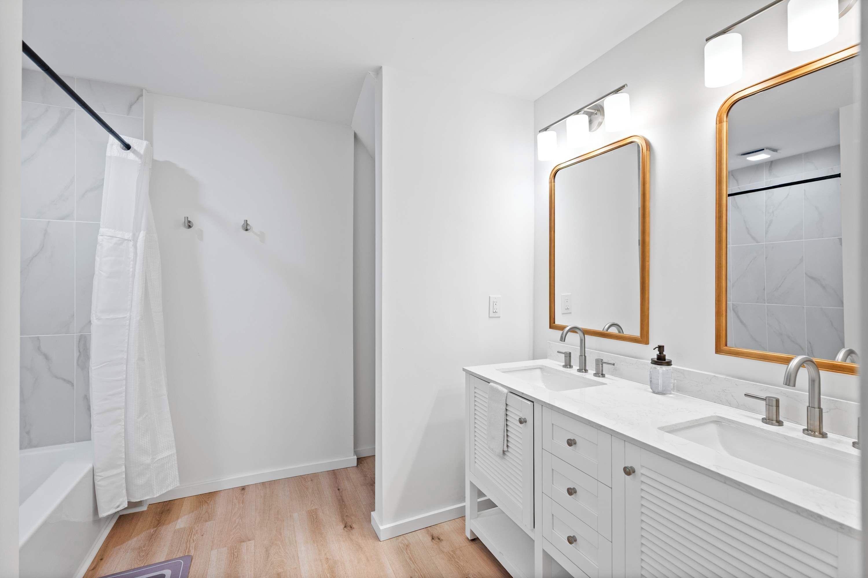 A modern bathroom with a shower, two sinks, and a large mirror.