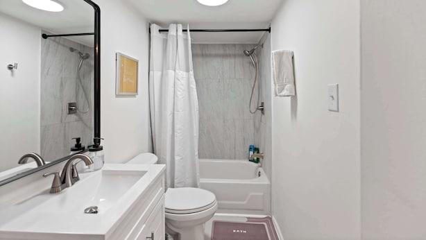 A modern bathroom with a white sink, toilet, and bathtub. - Rivers Edge Retreat For 10ppl (Dayton)