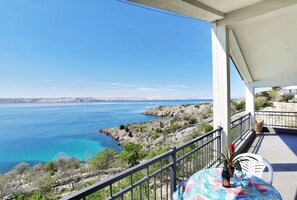 A balcony with a view of a coastal landscape, including a body of water and rocky terrain. - Apartments Adria (Karlobag)