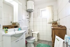Une salle de bain équipée de toilettes, d’un lavabo et d’une douche avec un chauffe-eau.