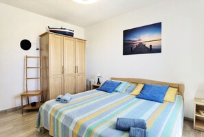 Une chambre à coucher avec un lit, une armoire, une chaise, un bureau et un tableau accroché au mur.