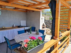 Un espace cuisine extérieur comprenant une table, des chaises et un barbecue.