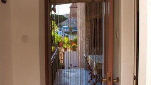 A room with a sliding door leading to a balcony with a view of a building and parked cars.