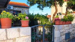 A stone wall with potted plants and a metal gate.