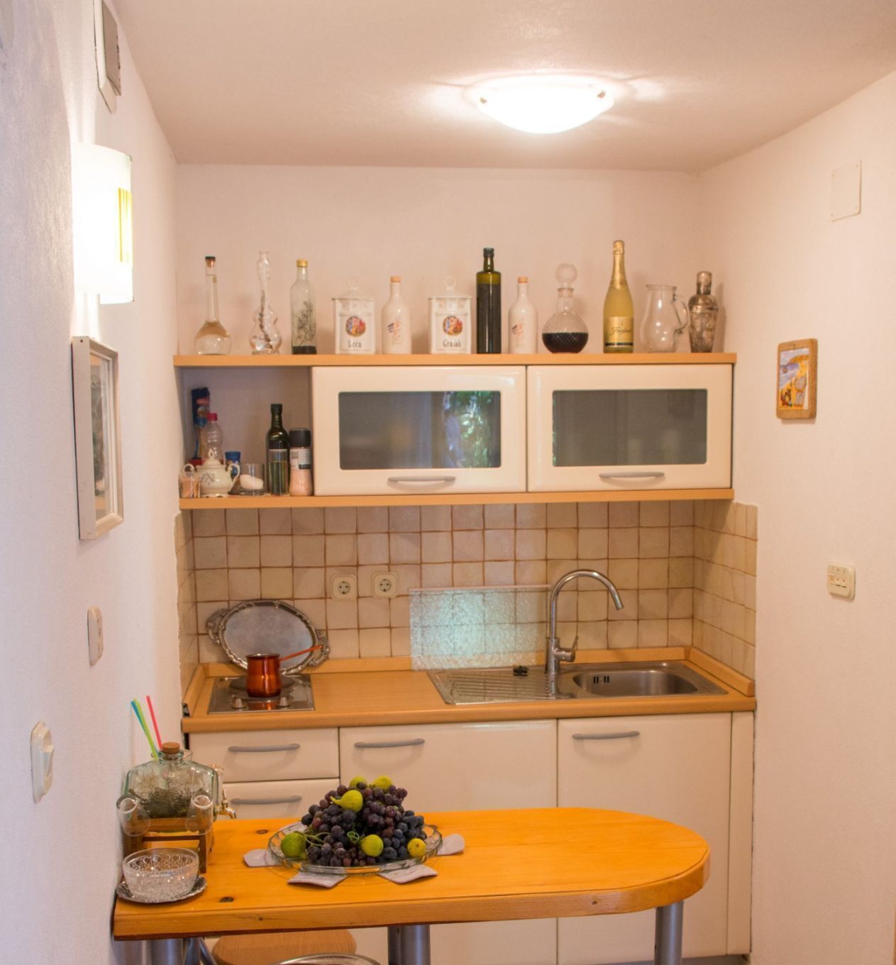 Cocina compacta con un lavamanos, dos microondas y una encimera con un bol de fruta.