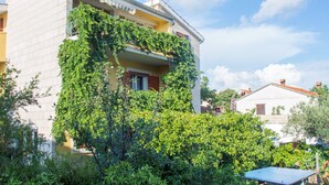 A building with a balcony covered in greenery, surrounded by dense foliage. - Apartment Kova (Stari Grad)