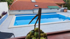 A swimming pool with a tiled roof and a basket of green fruits on a balcony. - Apartment Kova (Stari Grad)