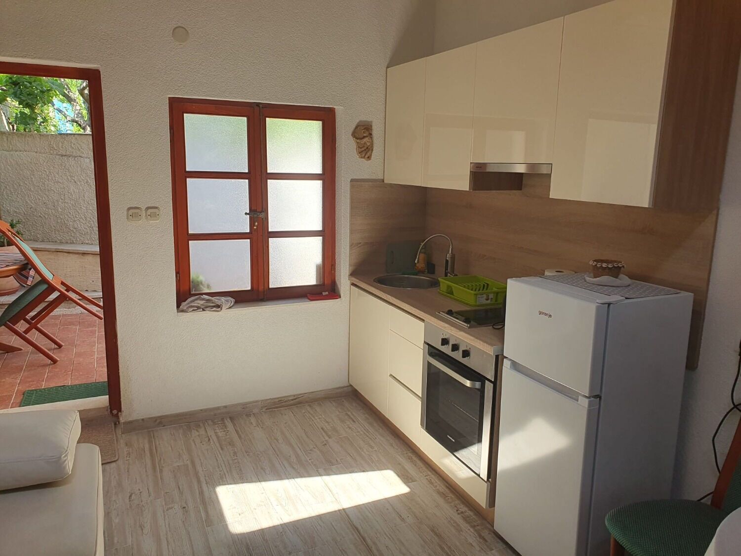 Eine kleine Küche mit Fenster, Spüle, Herd und Kühlschrank.