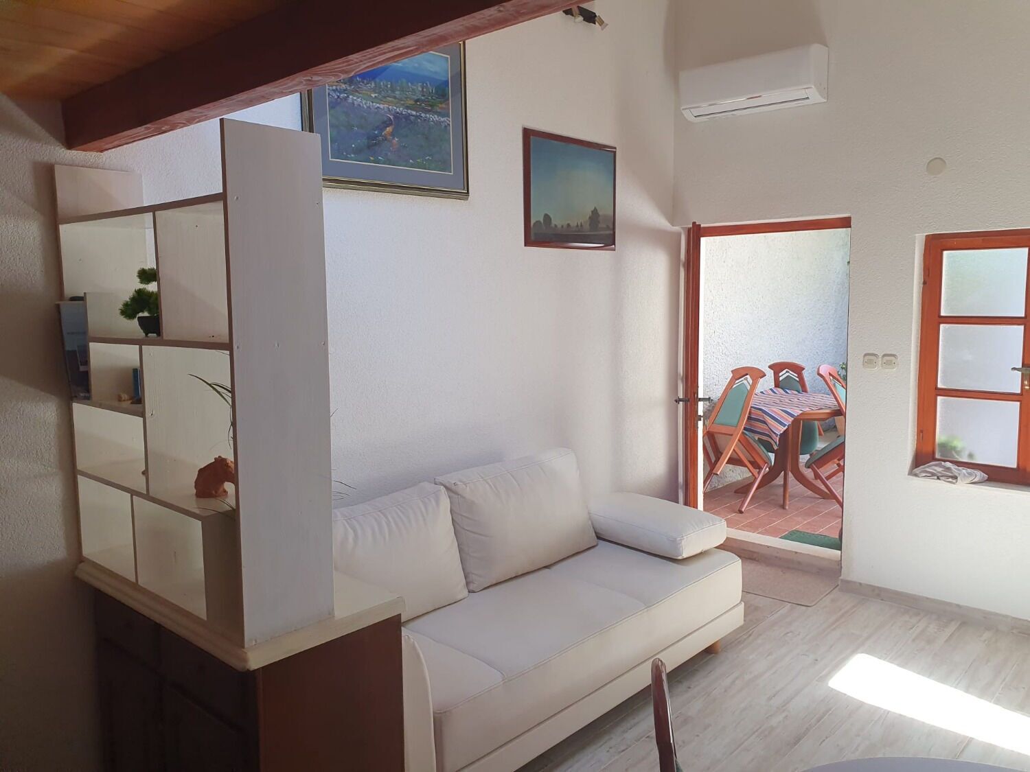 A living room with a sofa, a wooden cabinet, and a dining area with a table and chairs.