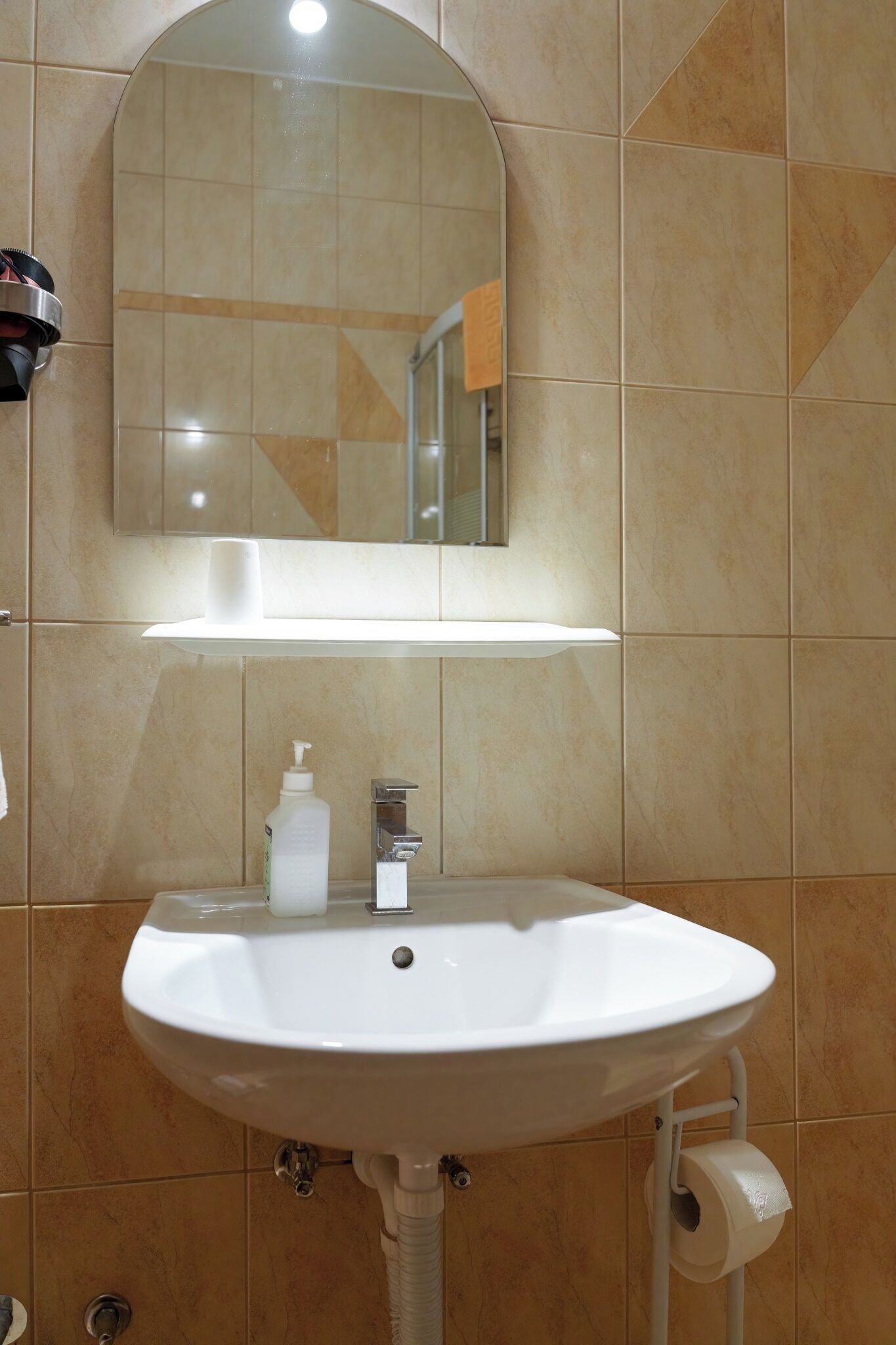 A bathroom with a white sink, a mirror above it, and a towel rack to the left.