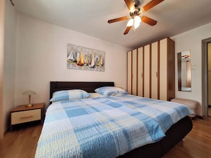 A bedroom with a bed, a nightstand, a ceiling fan, a wardrobe, a painting, and a mirror. - Apartment Emma (Novi Vinodolski)