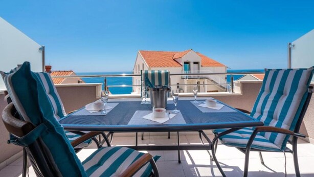 Una terraza con una mesa para dos, con vista al mar.