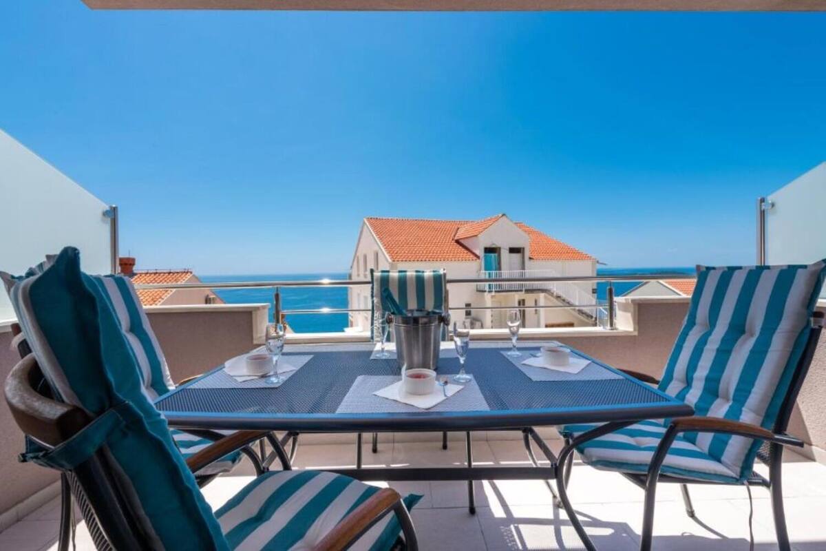 A terrace with a table set for two, overlooking the sea.