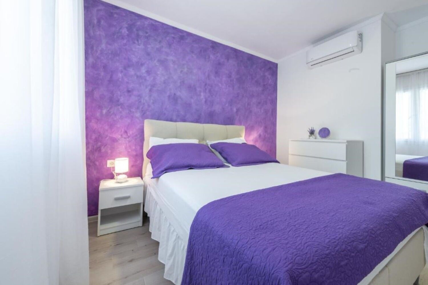A bedroom with a bed, nightstand, and dresser.