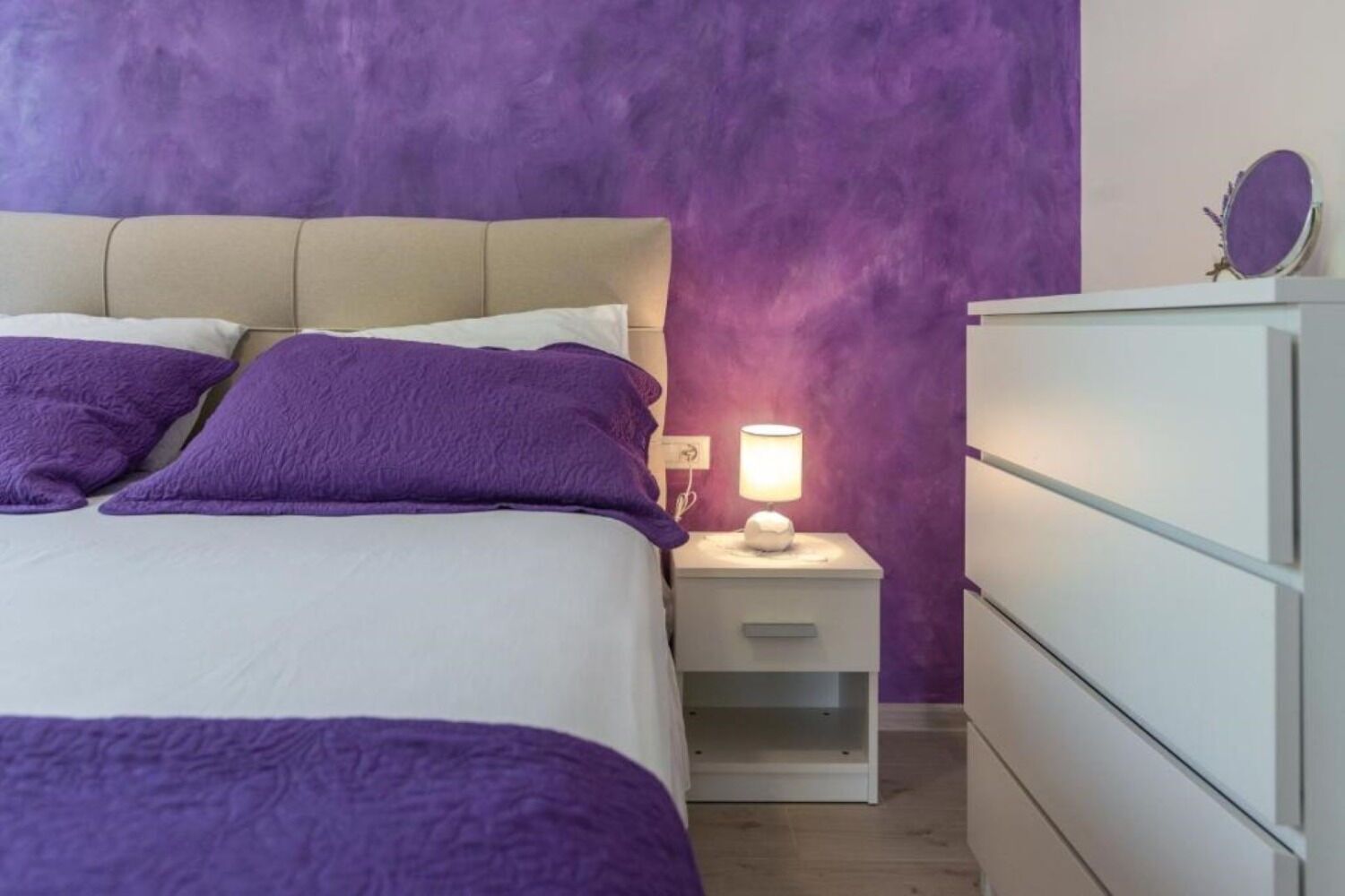 Ein Schlafzimmer mit einem Bett, einem Nachttisch mit Lampe und einer Kommode.