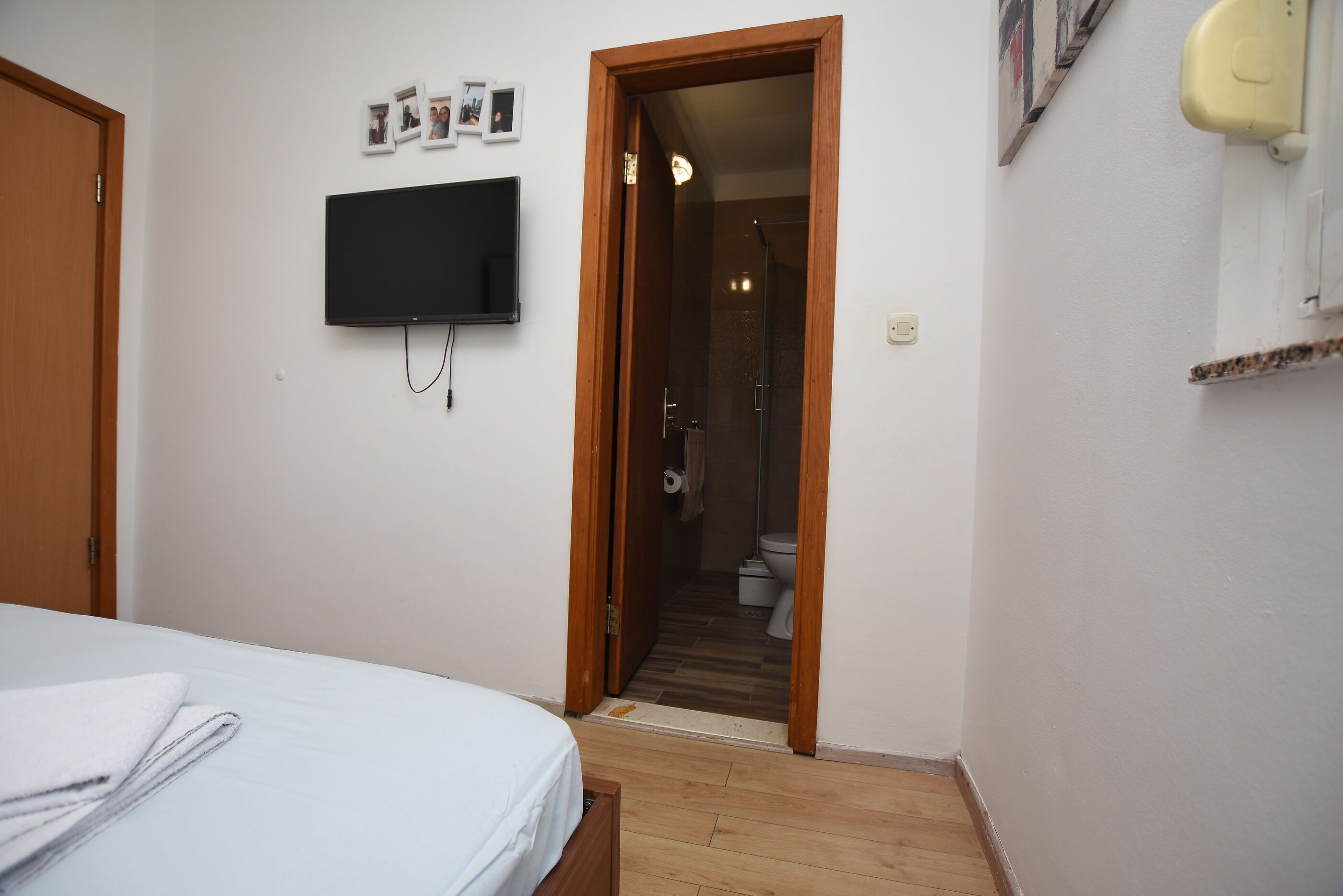 A bedroom with a bed, a television mounted on the wall, and a door leading to a bathroom.