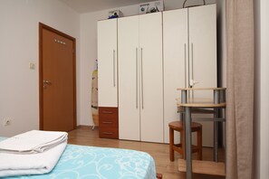 Ein Schlafzimmer mit Bett, Kleiderschrank, Schreibtisch und Stuhl.