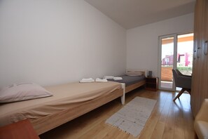 Een slaapkamer met een enkel bed, een stoel, een bureau en een schuifdeur die leidt naar een buitenruimte.