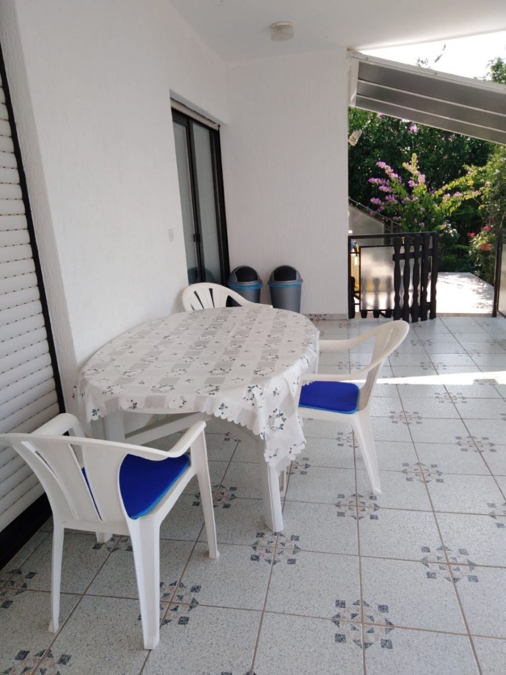 A small patio with a round table and four chairs, a window, and a door.