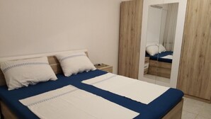 Ein Schlafzimmer mit einem Bett, zwei Kissen, einem Nachttisch, einem Spiegel und einem Kleiderschrank.