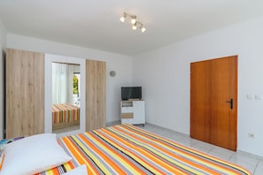 A bedroom with a bed, a TV, a wardrobe, and a wooden door. - Apartments Tomy (Medulin)