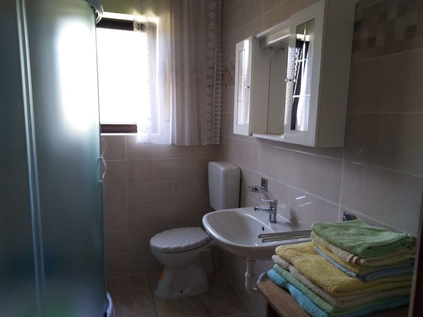 A bathroom with a toilet, sink, and a mirror above the sink.